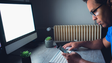 Young creative designer working at his desk, using laptop, concentrating on paperwork, choosing correct design, concept and sketches. In the night