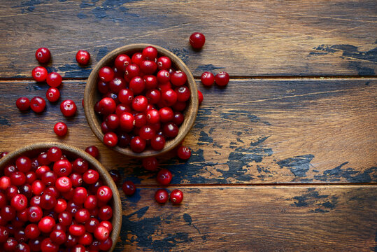 Fresh cranberry in a bowls on a rustic wooden background.