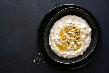Oat porridge with nuts and maple syrup for a breakfast. Top view with copy space.