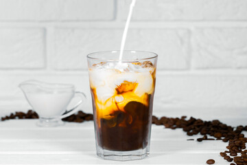 Milk Being Poured Into Iced Coffee on white background, Summer refreshment drink, Coffe Bean
