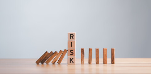 Wooden block stopping domino effect for business concept, reducing possible risks. Insurance, stability support. Legal protection of business interests. Favorable investment climate. Financial pillow.