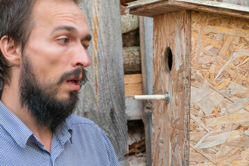 A man looks curiously into the birdhouse