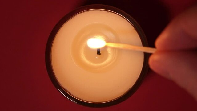 Top view on Burning candle close up on a dark background. Slow motion full HD video. Candle flame close up. Hand lights a candle with a match.