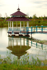 An exquisite gazebo with a bridge and railings above the water
