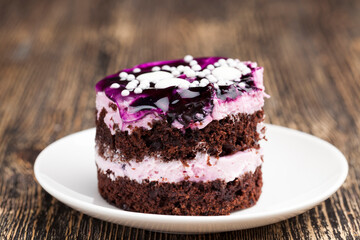 chocolate cake with cream covered with purple berry jam