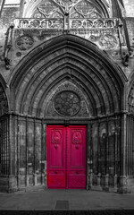 The doorway into the Bayeux Cathedral, a medieval church in France, is seen in bright red selective colour.