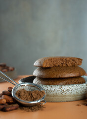 Gluten free, Vegan Homemade Chocolate Chip cookies from cocoa in a ceramic bowl.Organic product:cocoa powder, beans on a beige,dark background.Delicious healthy eat and cocoa products, during dessert