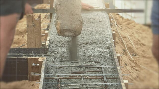 Pouring ready-mixed concrete in formwork with reinforcement. Wet cement pours to civil building foundation, close up.
