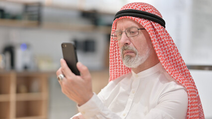 Portrait of Old Arab Businessman Browsing Internet on Smartphone 
