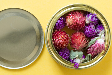 Gomphrena globosa or globe amaranth arranged inside a metal ring-lid on yellow