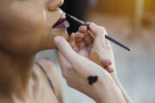 Makeup artist doing a makeup for photo shoot. Color swatch in hand. Latin woman with black eyes. Female portrait. Close up of hands near face.