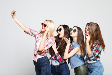 four happy teenage girls with smartphone taking selfie