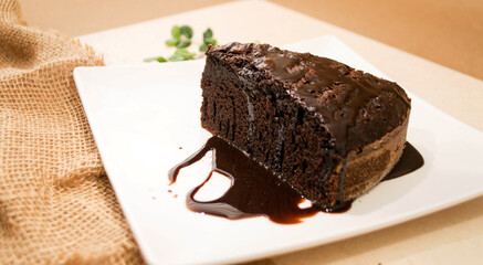 Pastel de Chocolate humedo bañado en chocolate amargo sobre un plato blanco 
