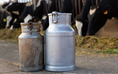 Image of two milk canisters standing on a farm in a cowshed. Close-up image