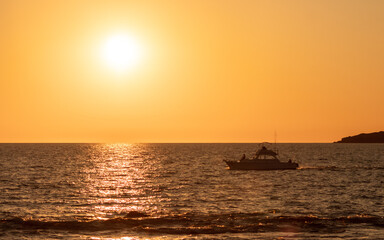 People on yacth in the sea in the sunset island in the background silhouette