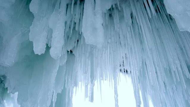 Inside the ice cave, the white translucent icicles of different thicknesses. North line of Olehun Island, Lake Baikal, ice field icicle view. Russia. Jan. 2019