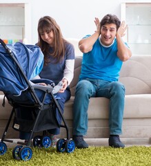 Young parents with their newborn baby in baby pram sitting on th