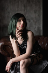 Stylish young woman with green in a black dress. Portrait of a beautiful girl with green hair