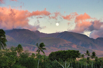 Full moon rising over the west maui mountains at sunset.