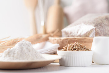 Whole wheat grains and wheat flour on white background. Natural organic products, healthy baking ingredients.