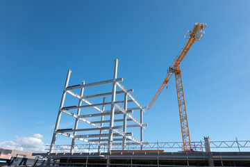 Fototapeta na wymiar heavy steel frame rising into blue sky as new building being constructed