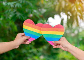 Couple hearts shown on LGBTQ hand. Out of focus background.