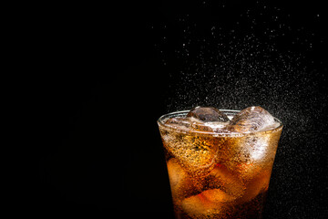 soft drink in cola glass with ice cubes on a dark black background