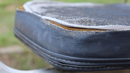 Old worn out leather seats. Weathered and damaged black leather upholstery with sponge inside....