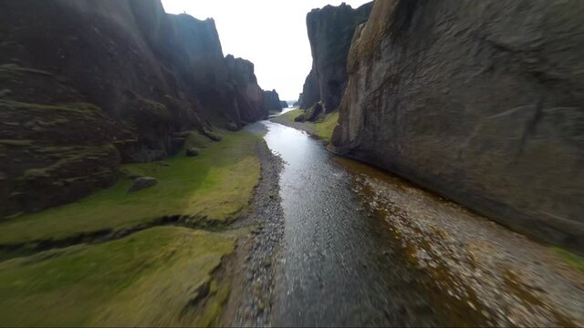 Low altitude FPV drone proximity flight over a river going through a canyon in Iceland
