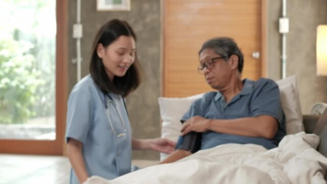 Blur focus VDO of female doctor checking health of Asian elderly male patient at home as medical service for visiting sick older people after retirement, medical support, caregiver from professional.
