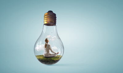 Business woman doing yoga in lotus pose inside light bulb