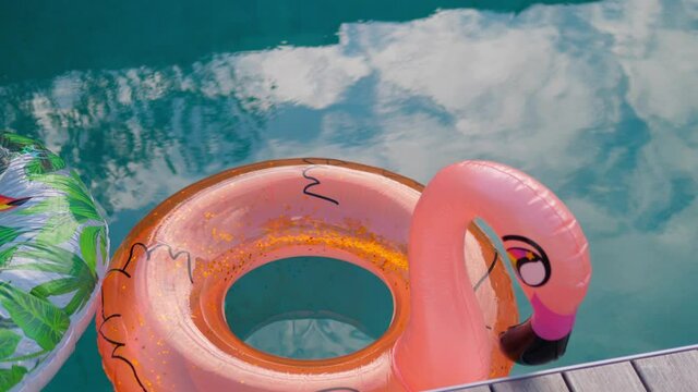 Vacation travel concept with inflatable orange flamingo float toy mattress in luxury swimming pool.Luxury lifestyle summer holidays travel background video.Inflatable toy of flamingo in swimming pool.