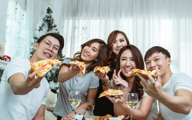 Group of asian people joining party at home, talking and eating pizza together. Lifestyle Concept.