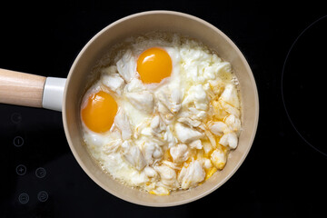 homemade sunny side up fried eggs with crabmeat in pan on stove, gourmet food recipe, good work from home lunch idea, egg white and egg yolk in cooking, black background