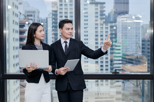 Two office employees are working in front of transparent computer screen and controlling it with gesture user interface. Photo suites to be used in photo composition for business or finance concept.