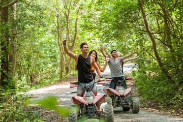 Group of young man and woman driving off road adventure with happy and smiling. Friends riding on ATV bike or quad bike on road along forest trail on mountain. Camping, jungle adventure concept © amorn