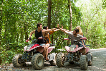 Group of young man and woman driving off road adventure with happy and smiling. Friends riding on ATV bike or quad bike on road along forest trail on mountain. Camping, jungle adventure concept