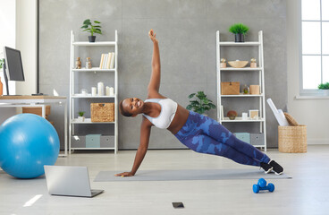 Portrait of smiling young African American woman in sportswear make plank do morning exercises...