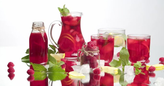Glassware of fresh raspberry lemonade and ingredients on white background