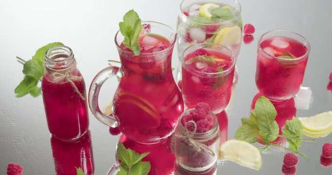 Glassware of fresh raspberry lemonade and ingredients on light background