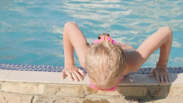 Portrait smiling girl in swimming pool, child in swimming glasses and inflatable sleeves. Summer travel hotel vacation or classes. Copyspace