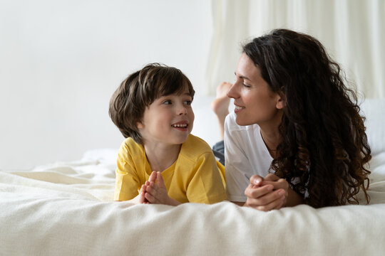 Young Single Parent Mother Enjoy Spending Weekend Morning Lying On Bed With Preschool Son Of 5, Talking Having Fun. Caring Mom Or Nanny Bonding With Little Child At Home. Loving Mum And Kid Together