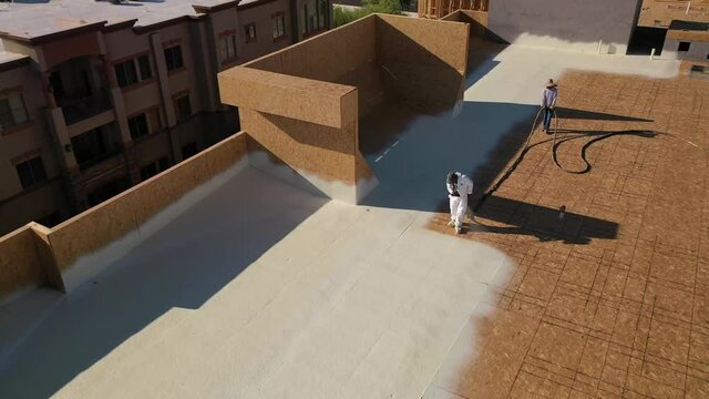 Commercial roofer spraying foam on roof drone video 4k