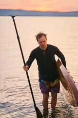 Man walking out the water with surf board
