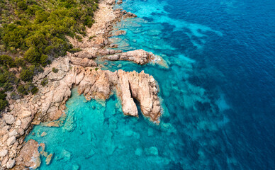 View from above, stunning aerial view of a green and rocky coastline bathed by a turquoise, crystal...