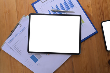 Flat lay, digital tablet with white screen and financial documents on wooden desk.