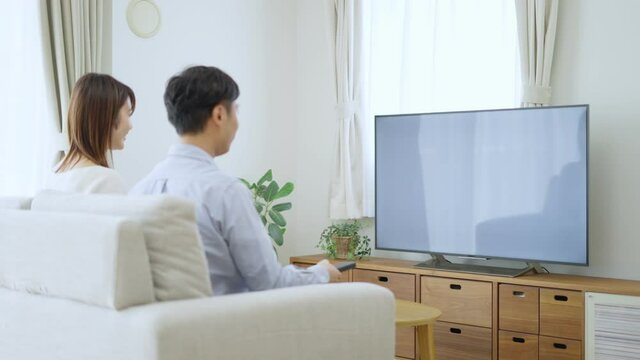 リモコンでテレビのチャンネルを変える夫婦・カップル
