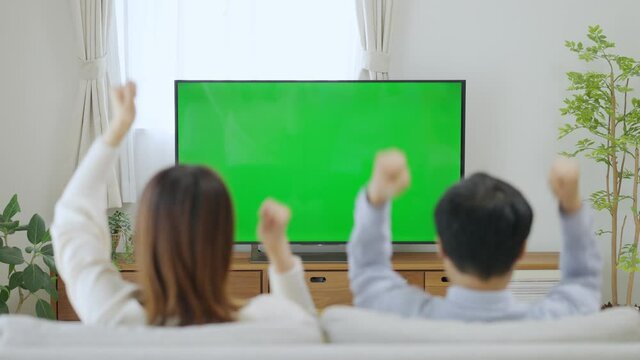 テレビでスポーツ観戦をし応援しているチームが勝ち喜ぶ夫婦・カップル（クロマキー）