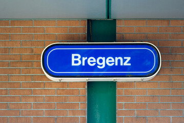 Sign at train station of Bregenz with red brick wall in the background on a sunny summer day. Photo taken August 14th, 2021, Bregenz, Austria.