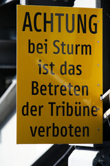 Yellow warning sign at open air opera stage with text warning do not enter stage during storm....